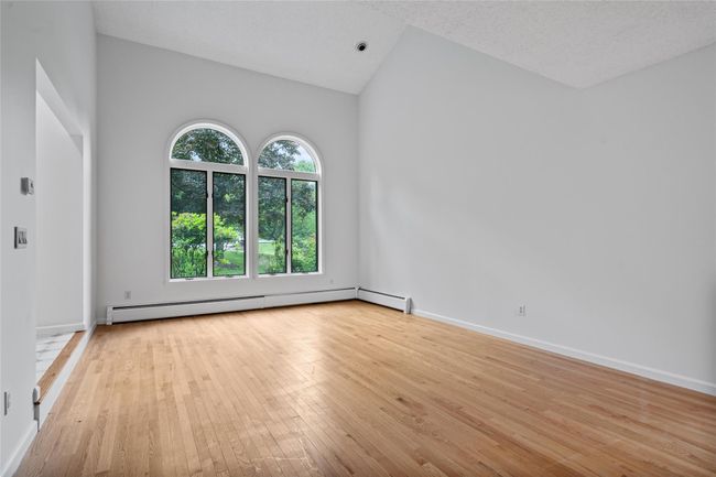 Unfurnished room featuring a baseboard heating unit, light wood-style flooring, and vaulted ceiling | Image 4