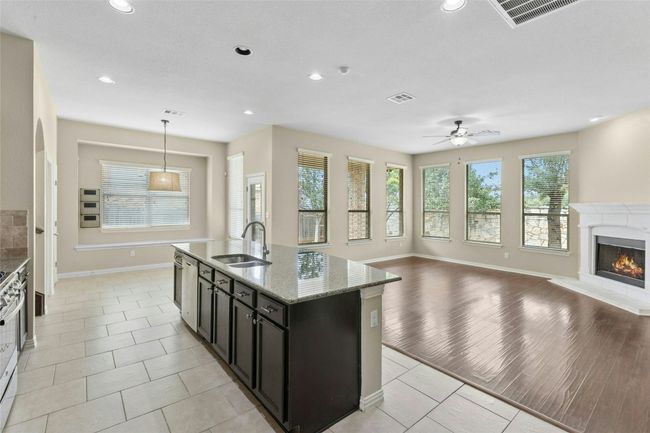 Kitchen featuring a sink, open floor plan, baseboards, a high end fireplace, and recessed lighting | Image 8
