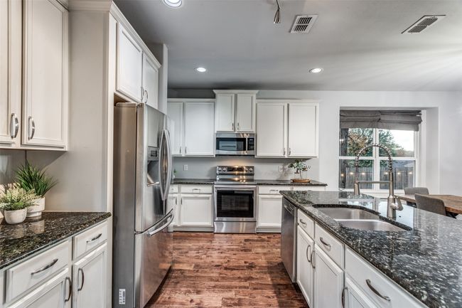 Kitchen featuring appliances with stainless steel finishes, recessed lighting, white cabinetry, dark wood-style floors, and dark stone countertops | Image 19