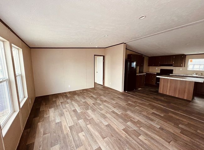 Kitchen featuring freestanding refrigerator, dark wood-style flooring, light countertops, open floor plan, and a textured ceiling | Image 14