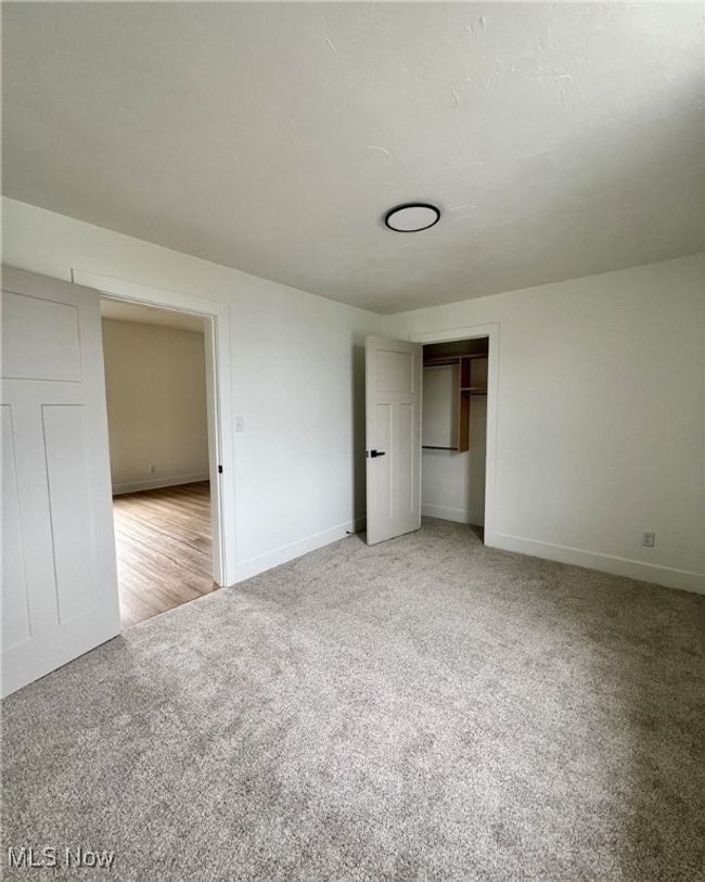 Unfurnished bedroom with a closet, light colored carpet, and baseboards | Image 14