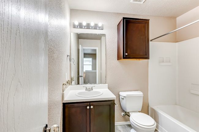 Full bath with vanity, bathing tub / shower combination, and a textured wall | Image 18