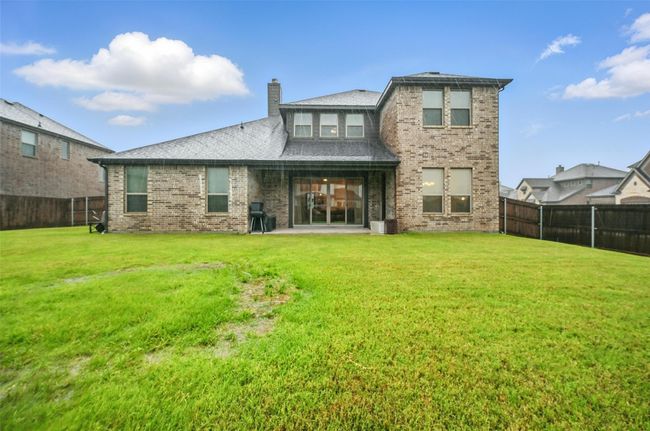 Rear view of property with a fenced backyard, brick siding, a chimney, and a patio area | Image 5