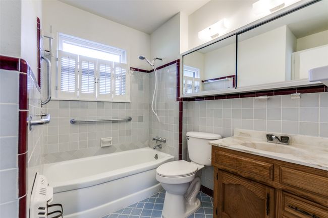 Full bathroom with shower / washtub combination, vanity, tile patterned floors, tile walls, and radiator | Image 15