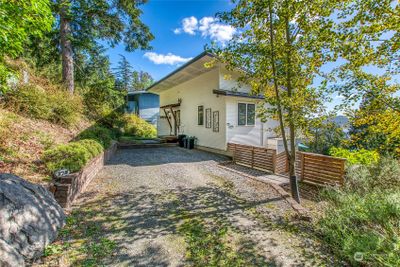 This modern yet cozy home sits on the hill above Eastsound Village and overlooks East Sound to the south. This shows the upper driveway, second floor entrance and stairway to the right leading to the main entrance. | Image 1