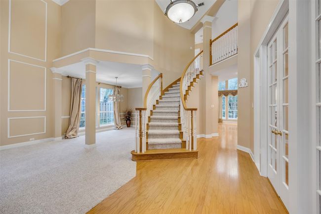 Entrance foyer with decorative columns, a chandelier, stairs, a towering ceiling, and light wood-type flooring | Image 4