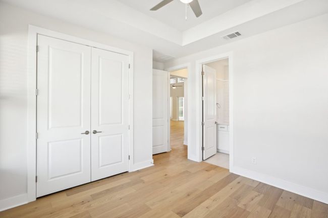 Unfurnished bedroom featuring light wood-style floors, a tray ceiling, a closet, visible vents, and baseboards | Image 19