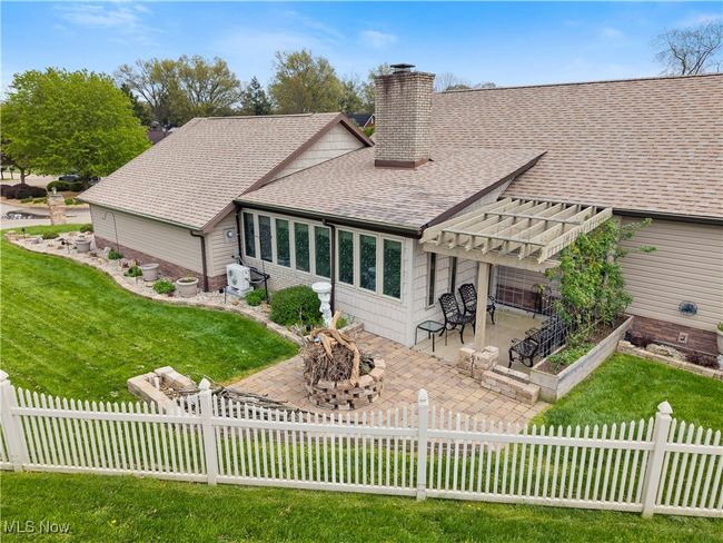 Rear view of house featuring a chimney, an outdoor fire pit, a shingled roof, a yard, and a patio | Image 4