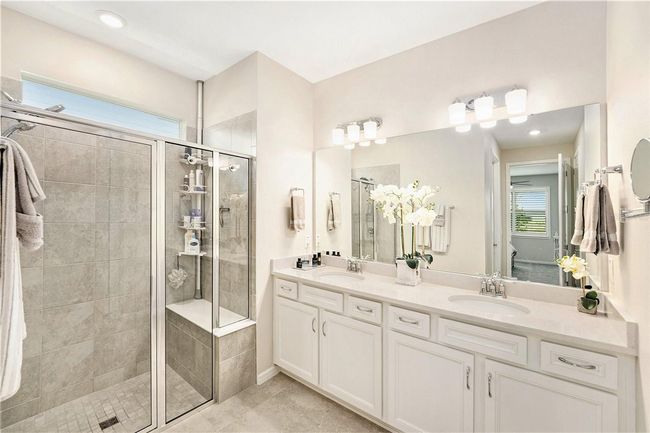 Oversized shower with built in sitting bench, dual sink vanity, private water closet, and luxury vinyl plank flooring. | Image 13