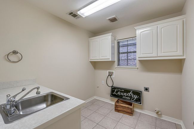 Clothes washing area featuring electric dryer hookup, cabinets, sink, washer hookup, and light tile patterned flooring | Image 6