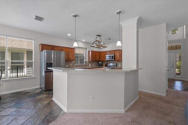 Bright, open-concept living/kitchen area with large windows while connecting seamlessly to the kitchen with a breakfast bar. | Image 11
