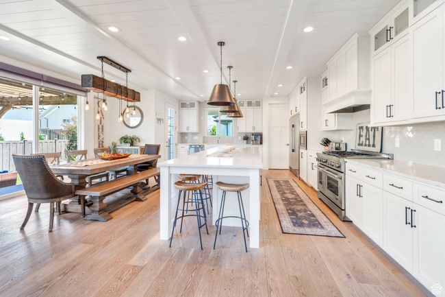 Kitchen featuring range with two ovens, light wood finished floors, tasteful backsplash, a kitchen island, and beam ceiling | Image 18