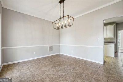 Tiled empty room with crown molding and a chandelier | Image 3