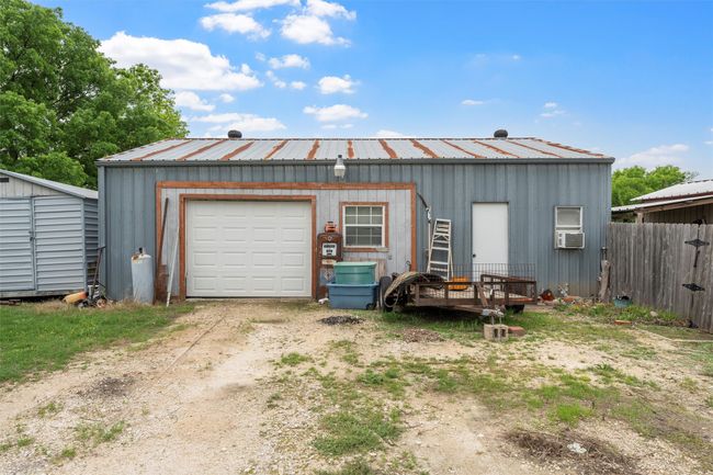 Detached garage with fence, cooling unit, and dirt driveway | Image 21