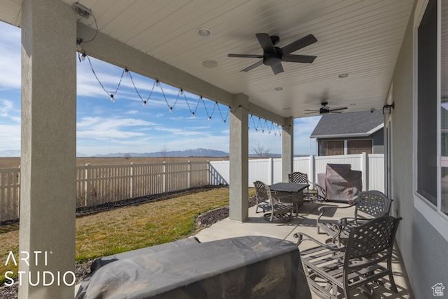 View of patio with a fenced backyard, outdoor dining space, a mountain view, and a ceiling fan | Image 43