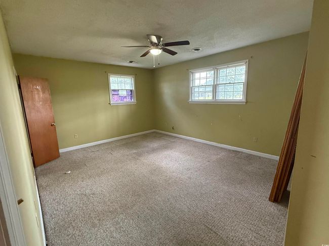 Carpeted empty room featuring plenty of natural light, ceiling fan, a textured ceiling, and baseboards | Image 12