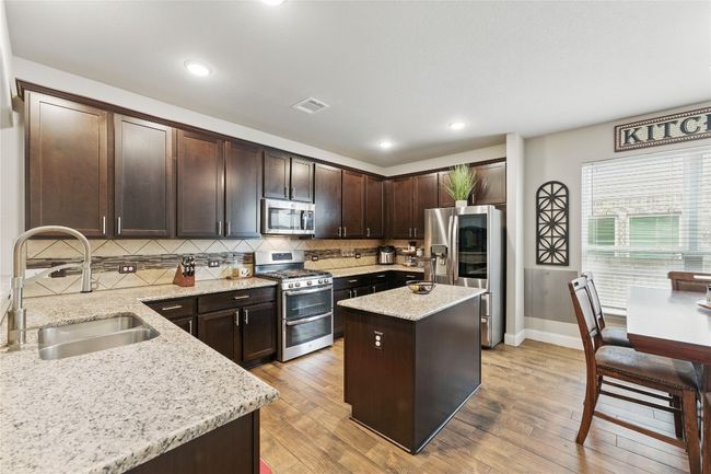 Kitchen featuring tasteful backsplash, visible vents, a sink, dark brown cabinetry, and stainless steel appliances | Image 10