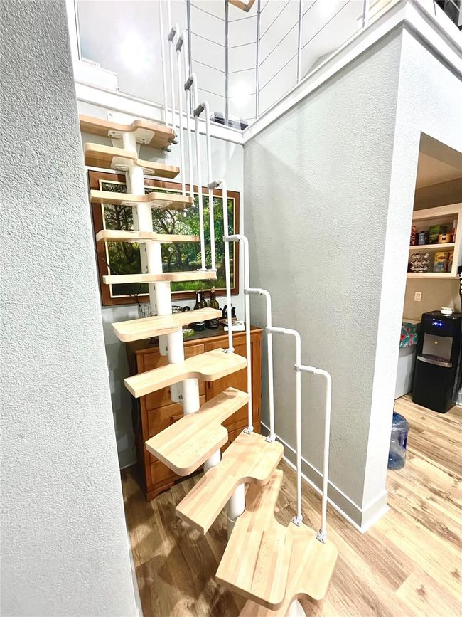 Staircase with a textured wall and wood finished floors | Image 13