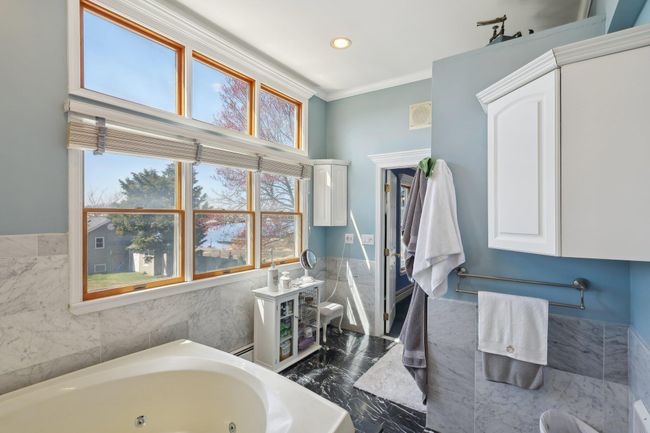 Bathroom featuring crown molding, toilet, a baseboard heating unit, a whirlpool tub, and lofted ceiling | Image 30