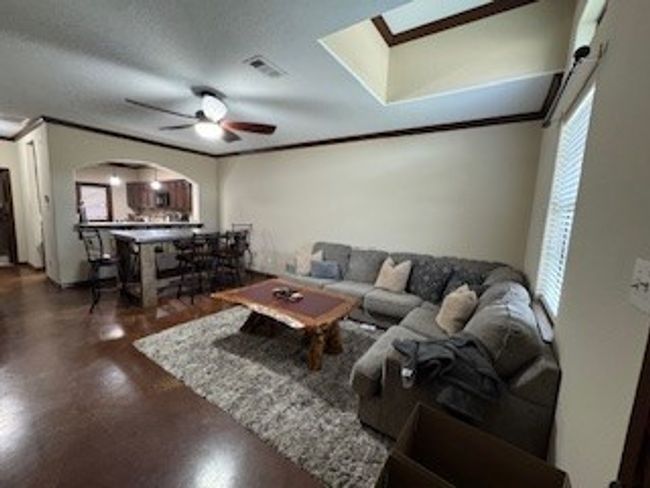 Living area featuring arched walkways, a skylight, a ceiling fan, and ornamental molding | Image 6