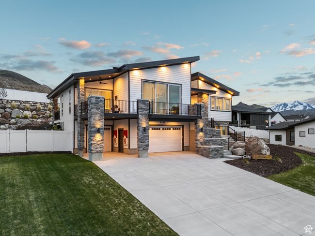 Modern home with a front yard, a garage, a balcony, concrete driveway, and fence | Image 71