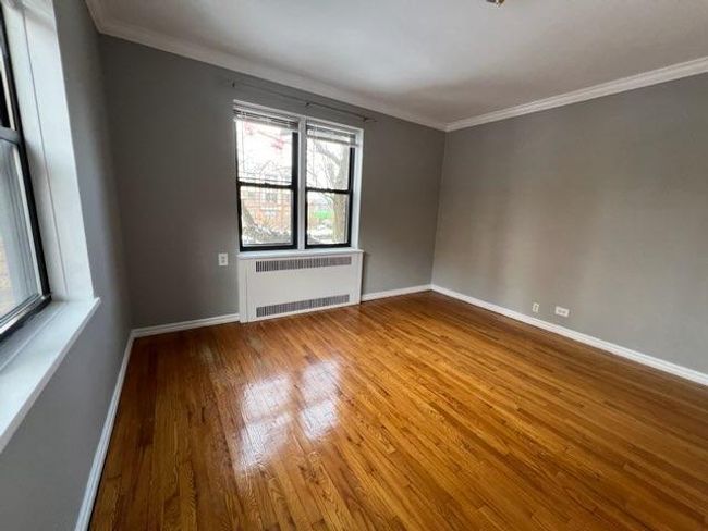 Spare room with radiator, wood finished floors, baseboards, and ornamental molding | Image 5