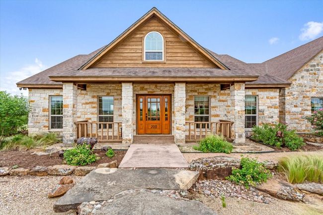 View of front of house featuring covered porch, stone siding, and roof with shingles | Image 6