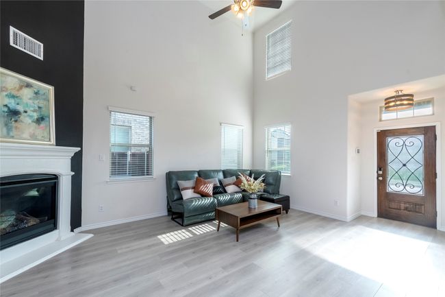 Foyer featuring light wood-style floors, a glass covered fireplace, a towering ceiling, and ceiling fan | Image 4