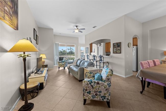 Living area with light tile patterned flooring, ceiling fan, arched walkways, baseboards, and visible vents | Image 17