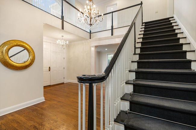 Staircase with a chandelier, a towering ceiling, wood finished floors, and baseboards | Image 14