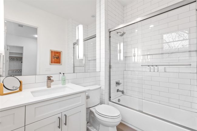 Bathroom featuring toilet, vanity, enclosed tub / shower combo, and tile walls | Image 24