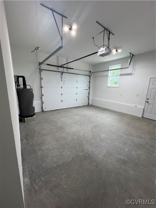 Garage featuring water heater and a garage door opener | Image 27