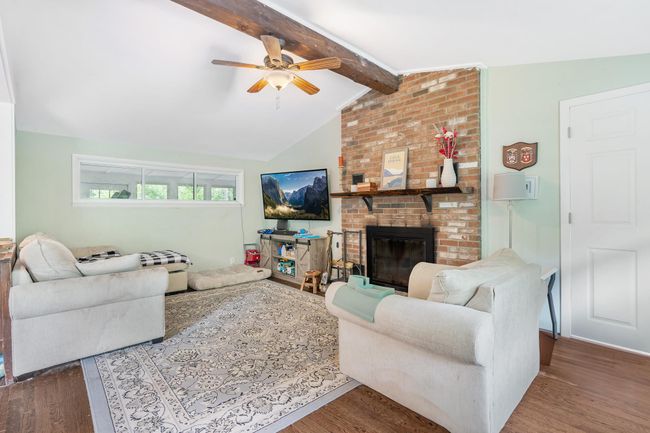 Living area featuring wood finished floors, ceiling fan, and a fireplace | Image 16