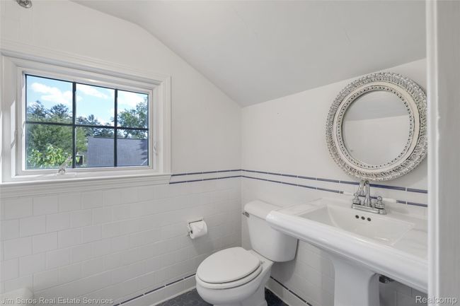 Half bath with tile walls, a baseboard heating unit, vaulted ceiling, and a wainscoted wall | Image 27