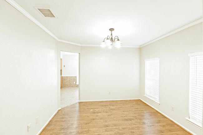 Spare room featuring a chandelier, light wood-type flooring, and crown molding | Image 7