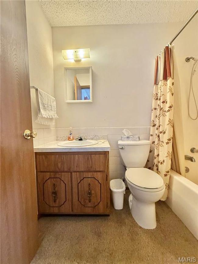 Bathroom with vanity, shower / tub combo with curtain, a textured ceiling, and tile walls | Image 35