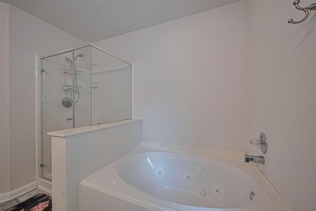 Enjoy a separate jetted soaking tub, updated standalone shower, upgraded quartz countertops, and all-new sinks, faucets, and vanity lights—plus the convenience of a private door leading to the backyard. | Image 22