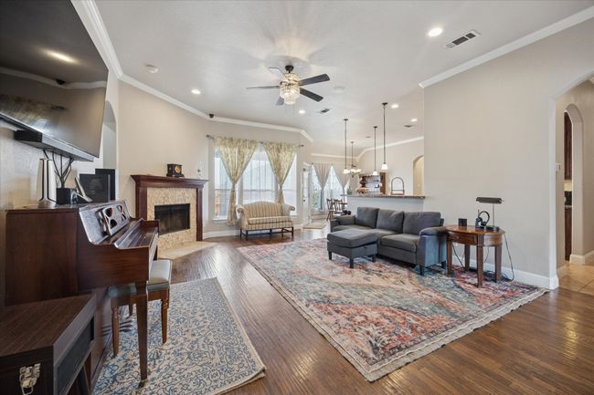 Living room with arched walkways, a ceiling fan, a tile fireplace, baseboards, and wood finished floors | Image 4