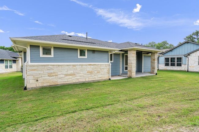 Rear view of property with a yard, stone siding, a patio, and a shingled roof | Image 25