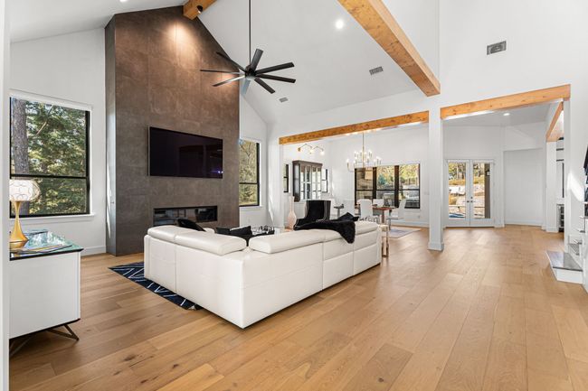 Living room with beamed ceiling, high vaulted ceiling, light wood-type flooring, and ceiling fan with notable chandelier | Image 4