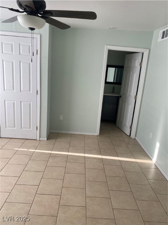 Unfurnished bedroom with light tile patterned floors, visible vents, baseboards, and a sink | Image 10