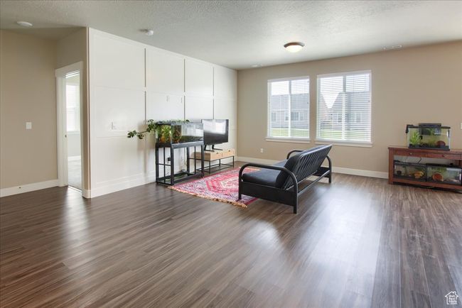 Living area featuring a textured ceiling, baseboards, dark wood-style floors, and visible vents | Image 7
