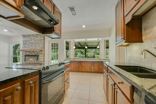 Kitchen with black electric range, a sink, plenty of natural light, and dark stone counters | Image 6