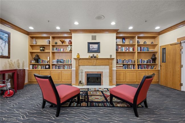 Common Living area featuring ornamental molding, a textured ceiling, visible vents, and dark colored carpet | Image 24