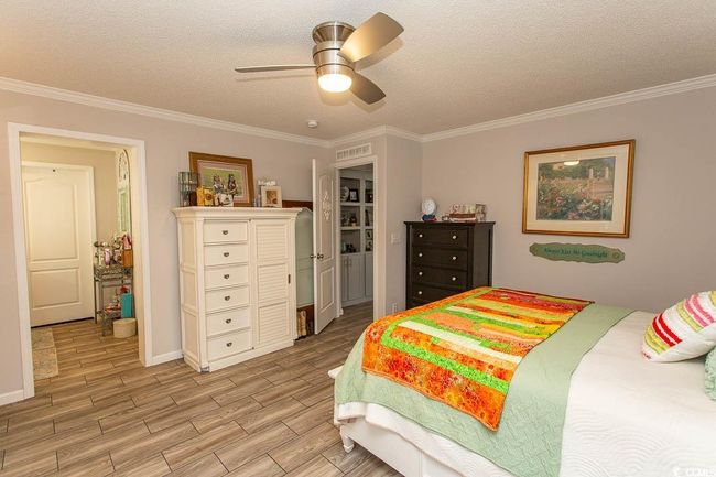 Bedroom featuring a textured ceiling, ceiling fan, crown molding, and light wood finished floors | Image 28