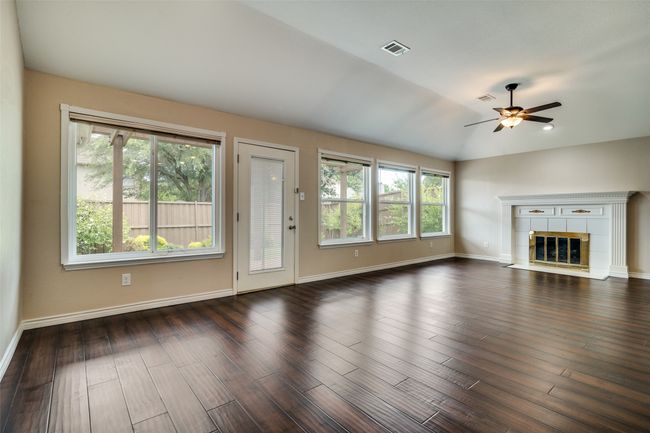 Unfurnished living room featuring vaulted ceiling, dark wood-style flooring, a tiled fireplace, and ceiling fan | Image 8