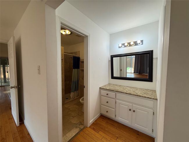 Bathroom featuring hardwood / wood-style flooring, a tile shower, and vanity | Image 11