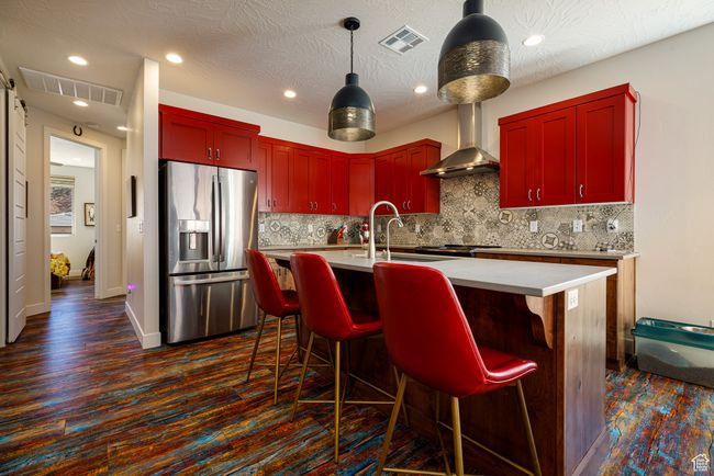 Kitchen with wall chimney range hood, stainless steel fridge, a sink, and visible vents | Image 16