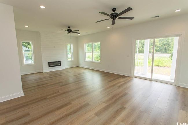 Unfurnished living room featuring ceiling fan, baseboards, wood finished floors, recessed lighting, and a fireplace | Image 8