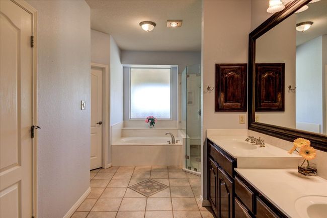 Enjoy a spa-like primary bath suite complete with soaking tub, separate shower, dual vanities, and dual closets. | Image 14